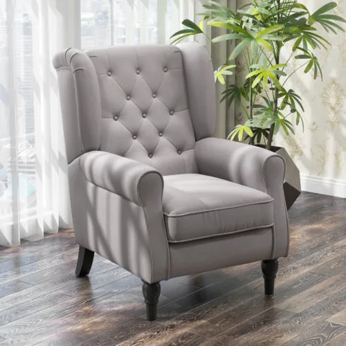 Grey wingback armchair with tufted back in a living room setting.