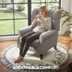 Person sitting on a grey retro accent chair by a window.