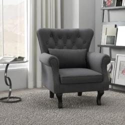 Dark grey Chesterfield-style accent chair with pillow in a modern room.