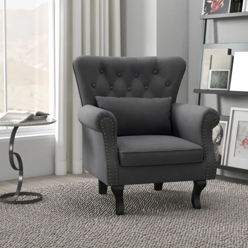 Dark grey Chesterfield-style accent chair with pillow in a modern room.