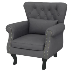 Dark grey tufted wingback armchair with pillow and wooden legs.