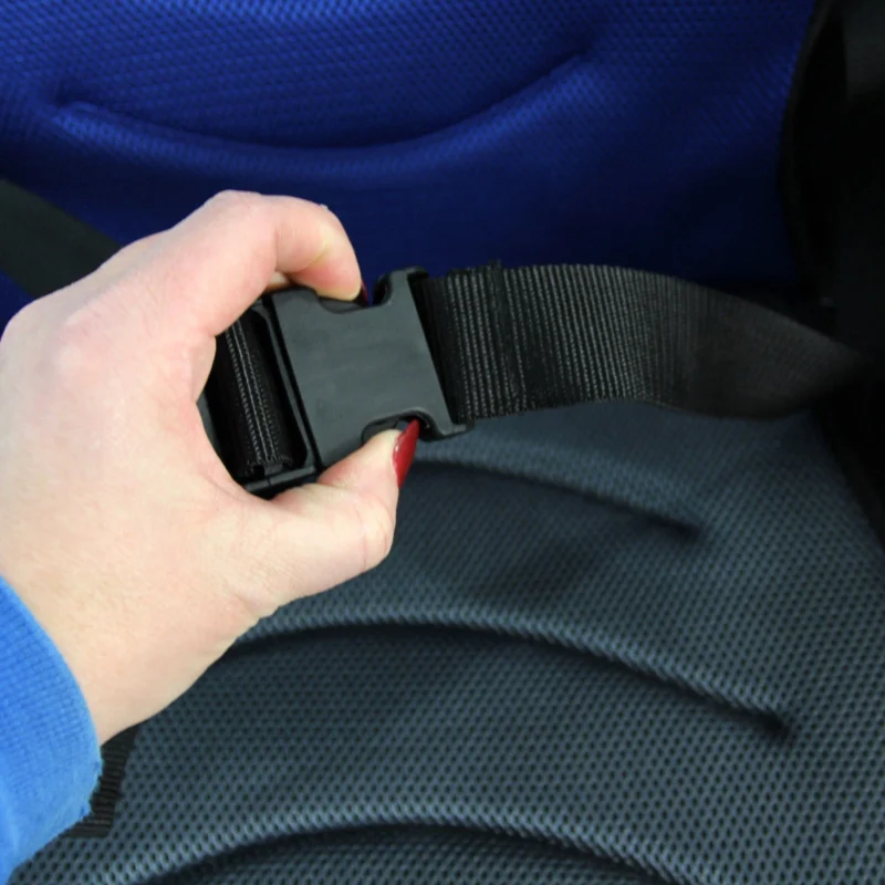 Close-up of a hand holding a wheelchair seatbelt buckle.