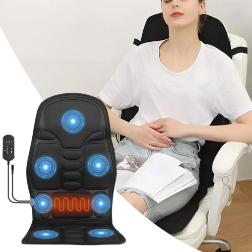 Person using a heated massage seat cushion on a chair with a remote control visible.