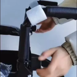 Hands adjusting the folding mechanism of a wheelchair.