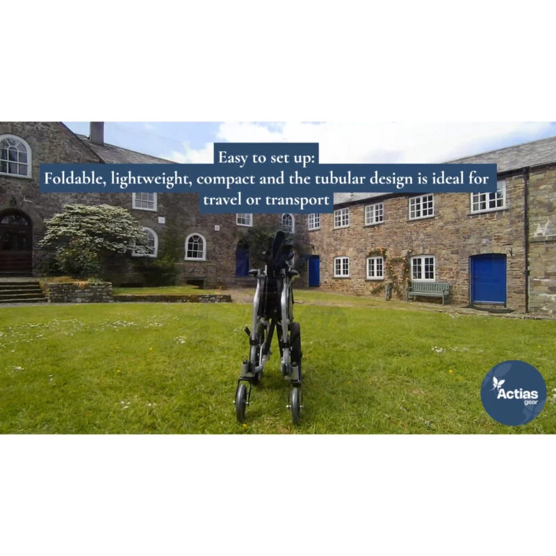 Folded aluminium wheelchair on grass with stone buildings in background.