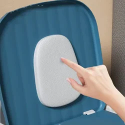 Hand touching the textured backrest of a blue bedside commode.