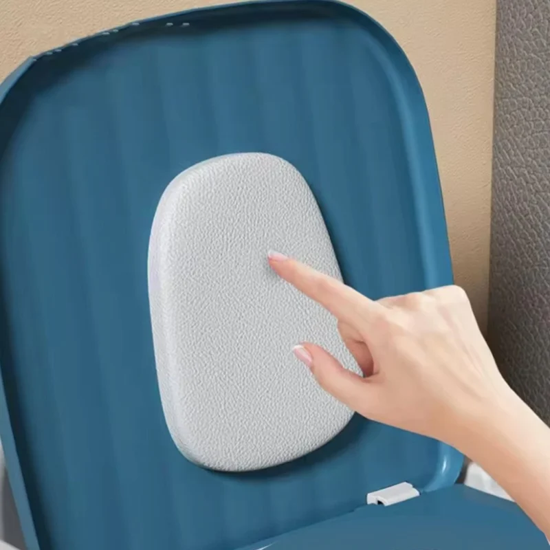 Hand touching the textured backrest of a blue bedside commode.