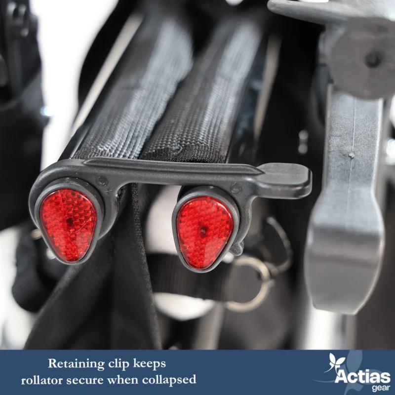 Close-up of a folded rollator with red reflectors and retaining clip.