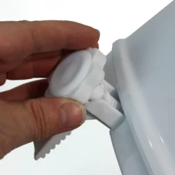 Close-up of a hand adjusting the clamp on a raised toilet seat.