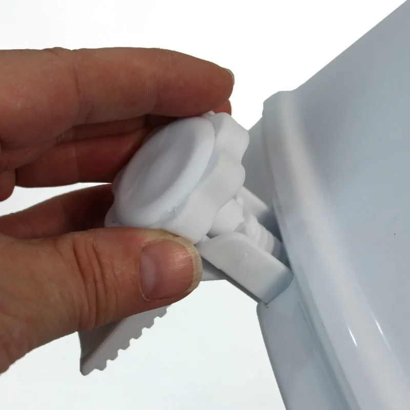 Close-up of a hand adjusting the clamp on a raised toilet seat.