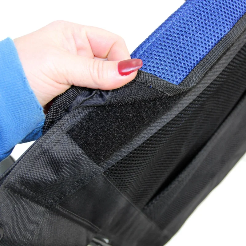 Close-up of a hand adjusting a blue mesh cushion on a wheelchair.